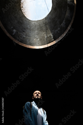 Abstract portrait of a man with a beard in the sun through a geometric window. Minimalism of the forms of light and shadow.