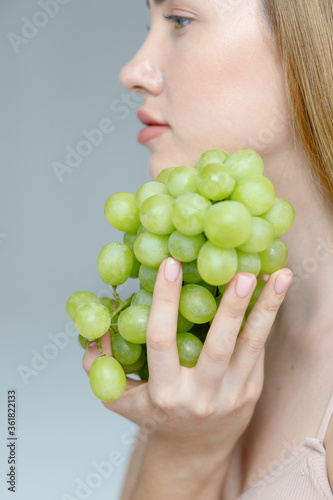 Lady Wearing Beige Swimsuit Model Isolated. Swim Suit Model. Rio Bottoms, Brabrassiere. Girls Briefs. Women Swimming Suit Underwear. Woman holds grapes in the chest and hugs it with both hands.