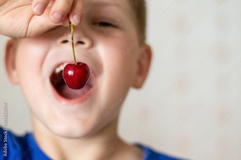 A boy with his mouth open eats a cherry A boy with his mouth open eats a cherry