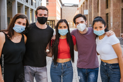 Group of young millennial friends taking a photo with smartphone and they wearing a facial masks avoid the infection from Coronavirus, Covid-19 - People having fun together - Concept of security