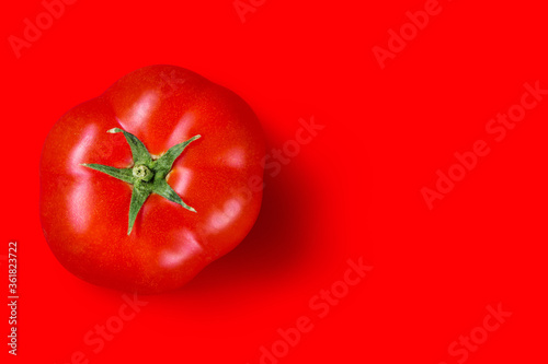 red ripe tomato on a red background, top view, concept photo