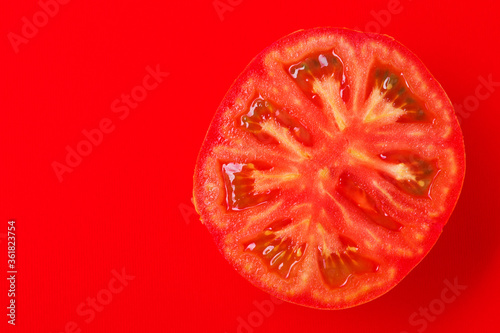 half a red tomato, slice up, on a red background, concept, flat lay