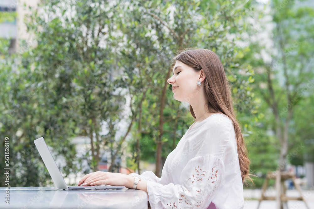 Fototapeta premium 屋外でノートパソコンを操作する女性
