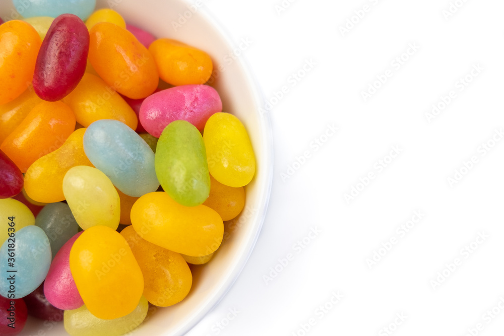 Colorful jelly beans candies in bowl backdrop, isolated on white. Copy space on right. Colorful jelly beans candies in bowl backdrop, isolated on white. Copy space on right.