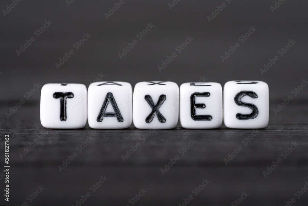 Word TAXES written on white block cubes on black background. Tax time concept Word TAXES written on white block cubes on black background. Tax time concept