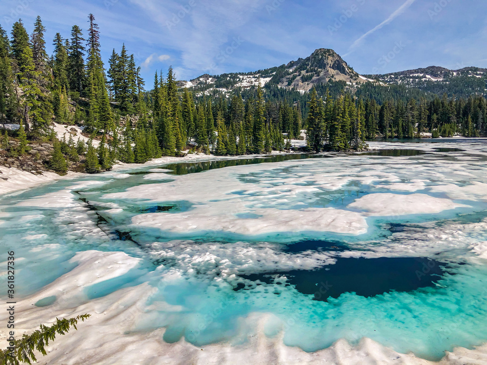 A warm summer day helps speed the melting of snow and surface ice on a high mountain lake.  