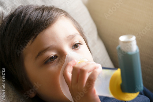 Poor boy have a problem with chest coughing holding inhaler mask, Child using the volumtic for breathing treatment, Kid having asthma allergy using the asthma inhaler, Healthcare and medicine concept