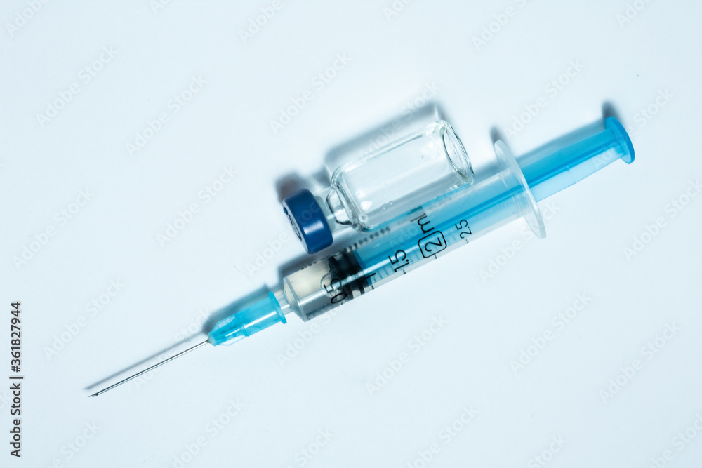 Glass medicine bottle with injection fluid with blue aluminium cap and syringe for vaccination. Cancer, painand diabetes treatment, pharmaceutical medicine concept . Glass medicine bottle with injection fluid with blue aluminium cap and syringe for vaccination. Cancer, painand diabetes treatment, pharmaceutical medicine concept .