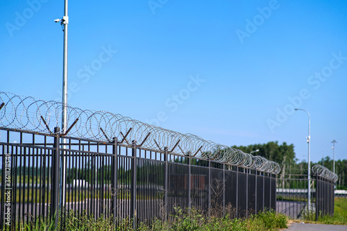 The restricted area is fenced with a fence with barbed wire. A fence around a restricted area with CCTV cameras on poles