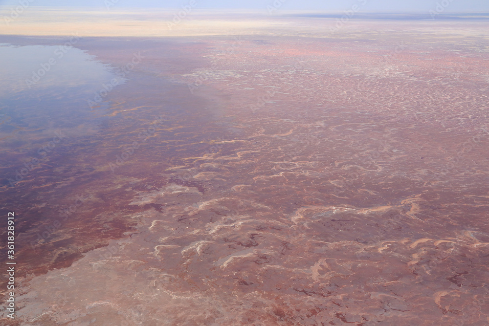 Aerial view of the salt pan and mineral crust with red algae of Lake Natron, in the Great Rift Valley, on the border between Kenya and Tanzania. The Rift Valley contains a chain of active volcanoes.