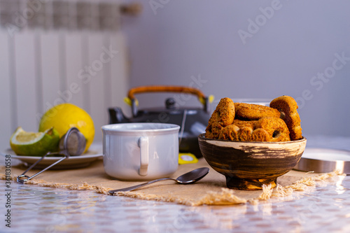 Taza de té negro con azúcar, limones y galletas en el fondo de la mesa rústica