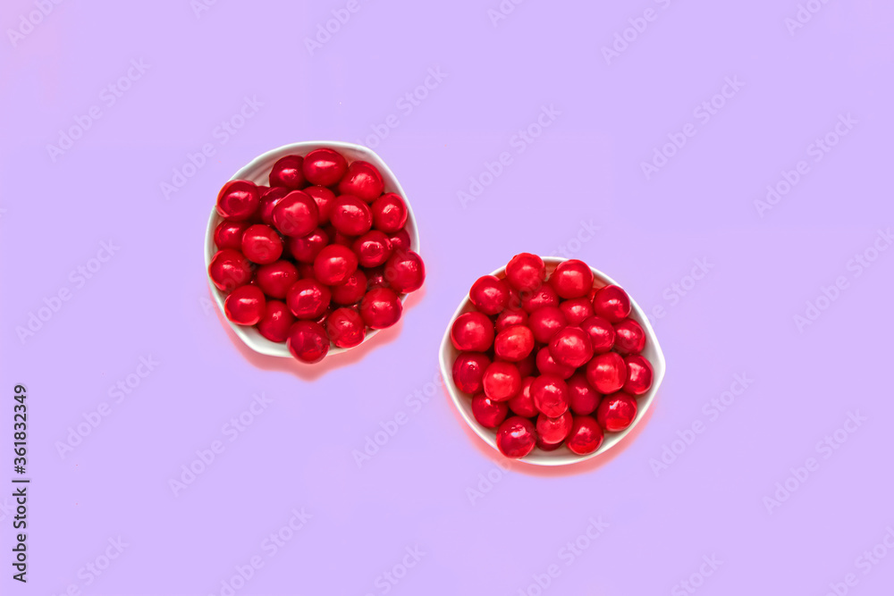 Cherry berries in two bowls on a purple background. Summer concept. Flat lay Cherry berries in two bowls on a purple background. Summer concept. Flat lay