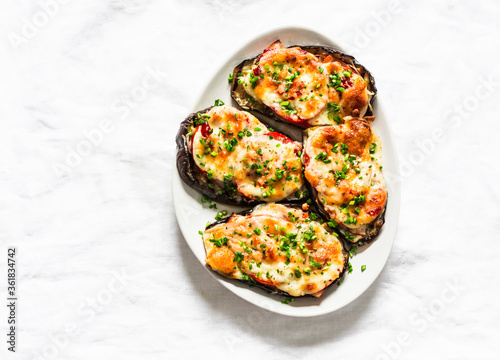Roasted eggplant steak with ham, tomatoes and mozzarella cheese - delicious appetizer, tapas on a light background, top view