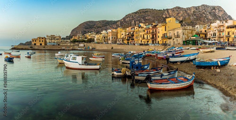 A panorama view of colourful fishing boats and the shoreline at Aspra Sicily at sunset on a summer's evening