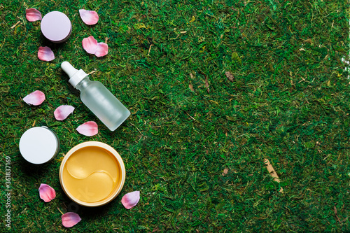 Various cosmetics on a spring background with green grass and petals