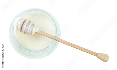 top view of wooden stick over glass jar with natural organic white honey isolated on white background