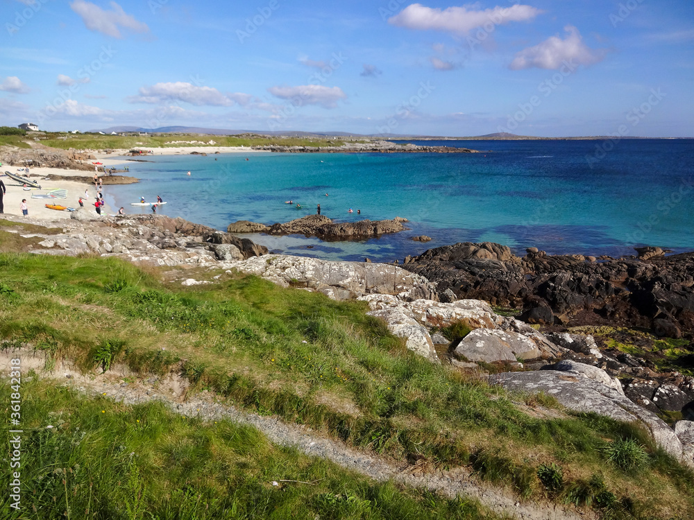 A view of the Irish coast near Clifden in Ireland showing the green grass, rocks and the blue ocean