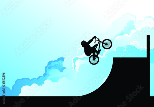 Silhouetted BMX rider performing stunts set against a blue cloudy sky background