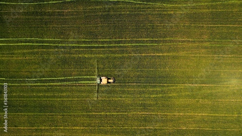 Fotografia, Obraz Birds-eye view of a tractor working in a green field