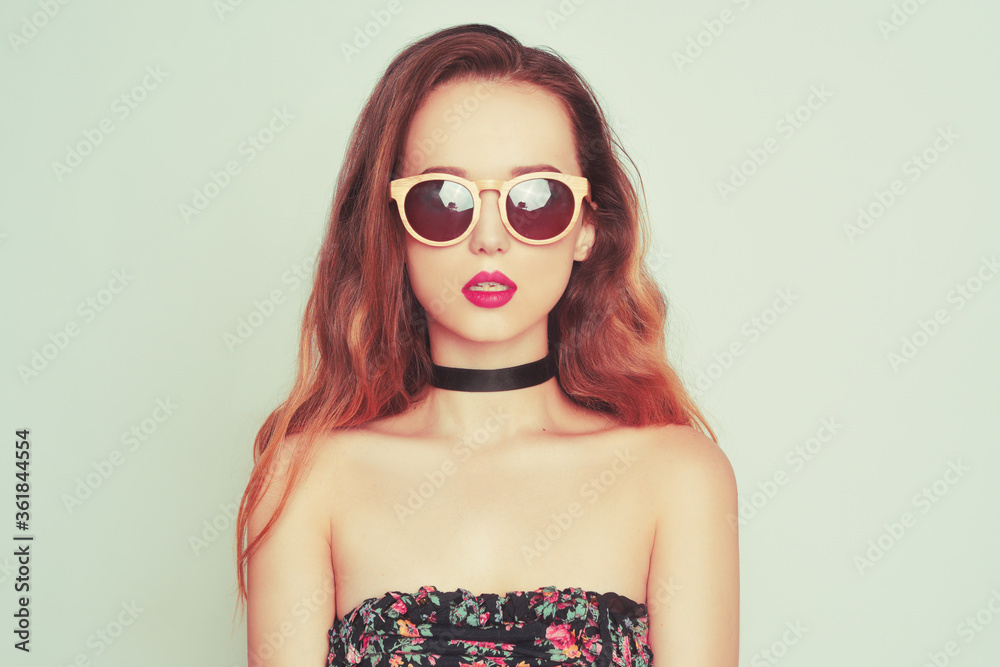 A girl in sunglasses and with long hair is looking directly at the camera. Model in a choker with big red lips in wooden glasses. Fashion A girl in sunglasses and with long hair is looking directly at the camera. Model in a choker with big red lips in wooden glasses. Fashion