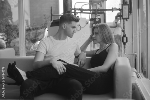 Couple on the couch black and white photo, stylish photo of love. Fashion photo of a couple, blonde girl with a guy. Perfume, love is in the air.