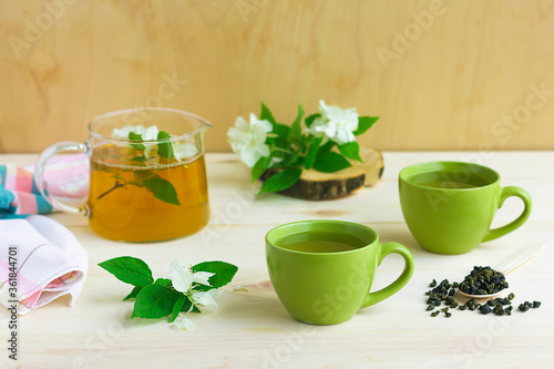 Composition, set with two cups of green herbal tea with jasmine flower and teapot