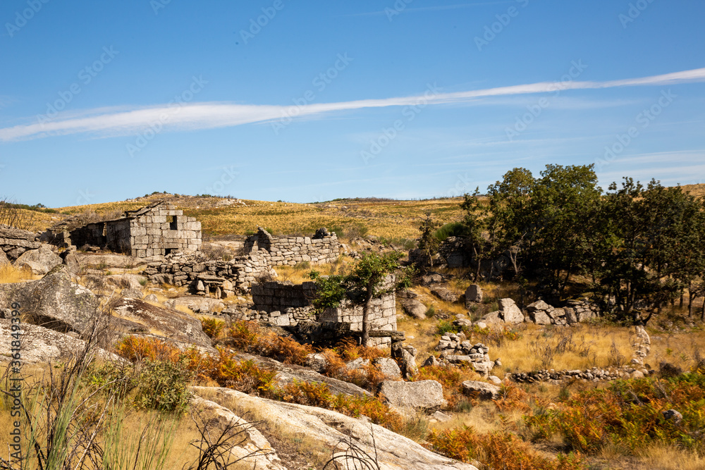 blue sky with long white cloud over ancient rural village with stone houses