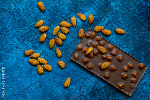 Chocolate chunks with hazelnuts isolated on blue background
