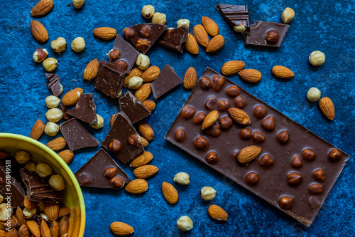 Chocolate chunks with hazelnuts isolated on blue background