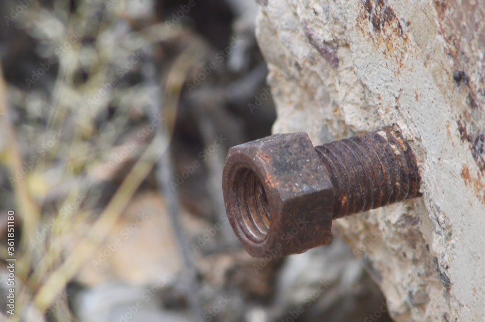 Rusted bolt protruding from concrete slab abandoned in the desert