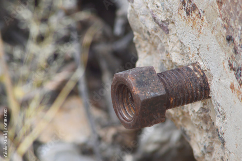 Rusted bolt protruding from concrete slab abandoned in the desert