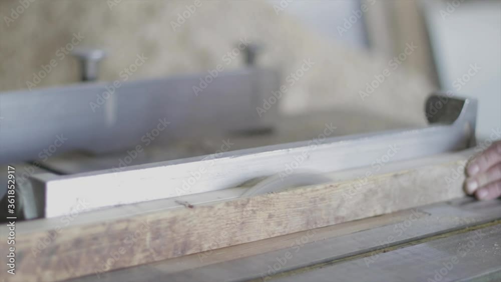 Cutting a long wooden plank on an electric saw in a carpenter's shop. Carpenter industry. Cutting a long wooden plank on an electric saw in a carpenter's shop. Carpenter industry.