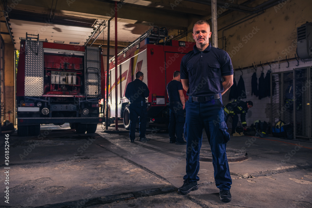 Portrait of handsome firefighter standing against trucks at fire station Portrait of handsome firefighter standing against trucks at fire station