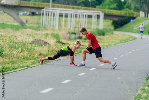Young couple warming up and stretching together in a park before running