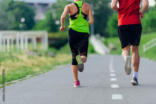 Rearview of caucasian female and male running outdoors on a road