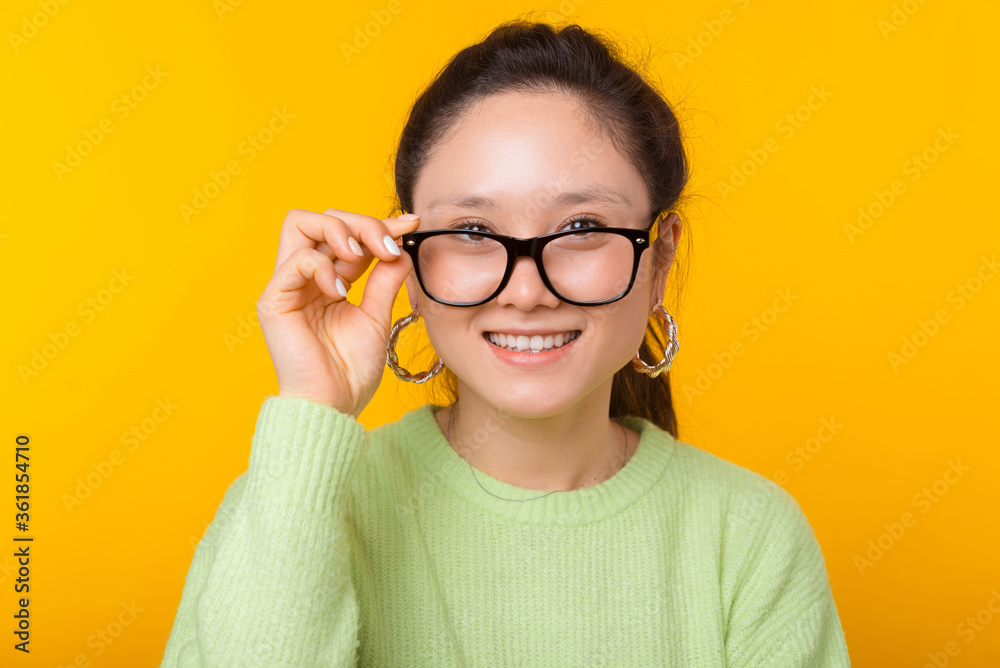 Close up portrait of a cute woman wearing glasses over yellow background