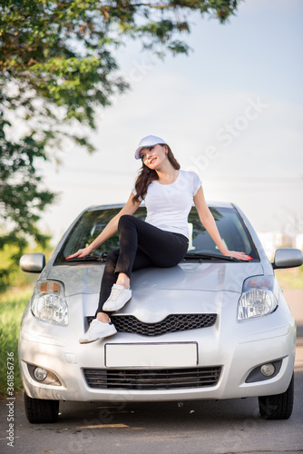 girl in sportswear and a baseball cap stands near a car on the road © Марина Шавловская