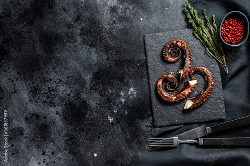 Grilled octopus tentacles. Fresh seafood. Black background. Top view. Copy space