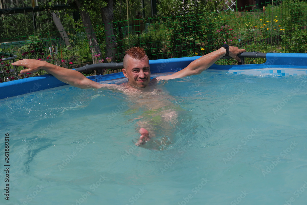 A young man is swimming in the pool.  Pool in the garden.  Summer vacation in the pool.