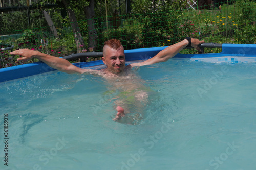 A young man is swimming in the pool.  Pool in the garden.  Summer vacation in the pool.