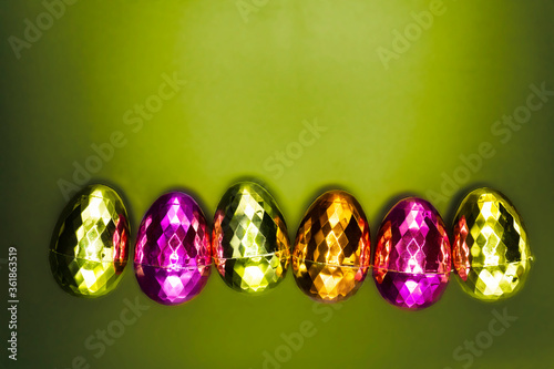 Colorful shiny Easter eggs isolated on green background