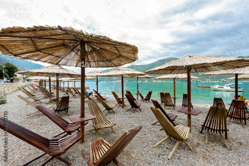 The empty beach. Beach wooden furniture  umbrellas. It s a nasty day. Montenegro  Kotor bay
