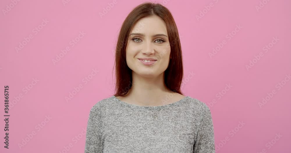 Portrait of cheerful young lady with dark hair smiling and looking at camera while posing in studio. Isolated over pink background. Concept of face emotions. Portrait of cheerful young lady with dark hair smiling and looking at camera while posing in studio. Isolated over pink background. Concept of face emotions.