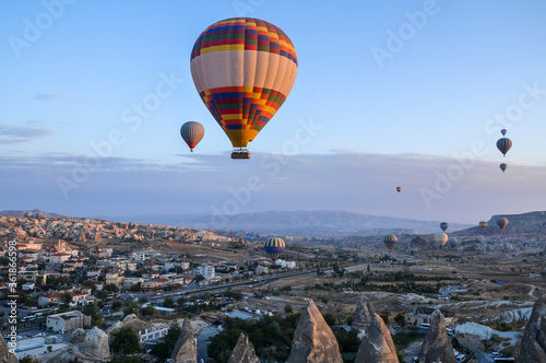 Color hot air balloons flying at sunrise over stone formations in valley of Cappadocia,Turkey