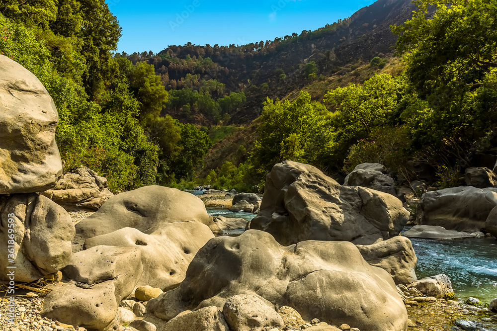 A view of the Alcantara river as it flows past large volcanic boulders near Taormina, Sicily in summer