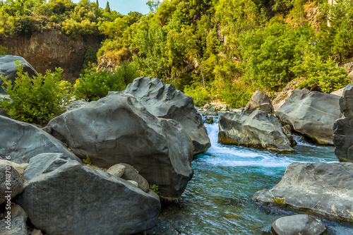 The Alcantara river has eroded a volcanic flow to leave large volcanic boulders on the riverbed near Taormina, Sicily in summer