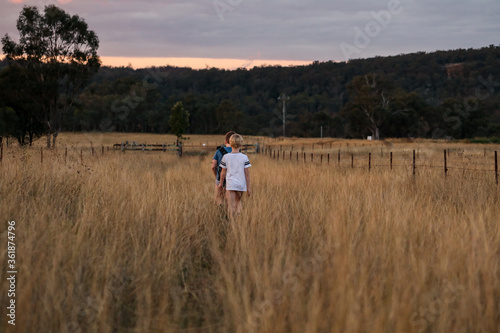 Young boys walking through field at sunset