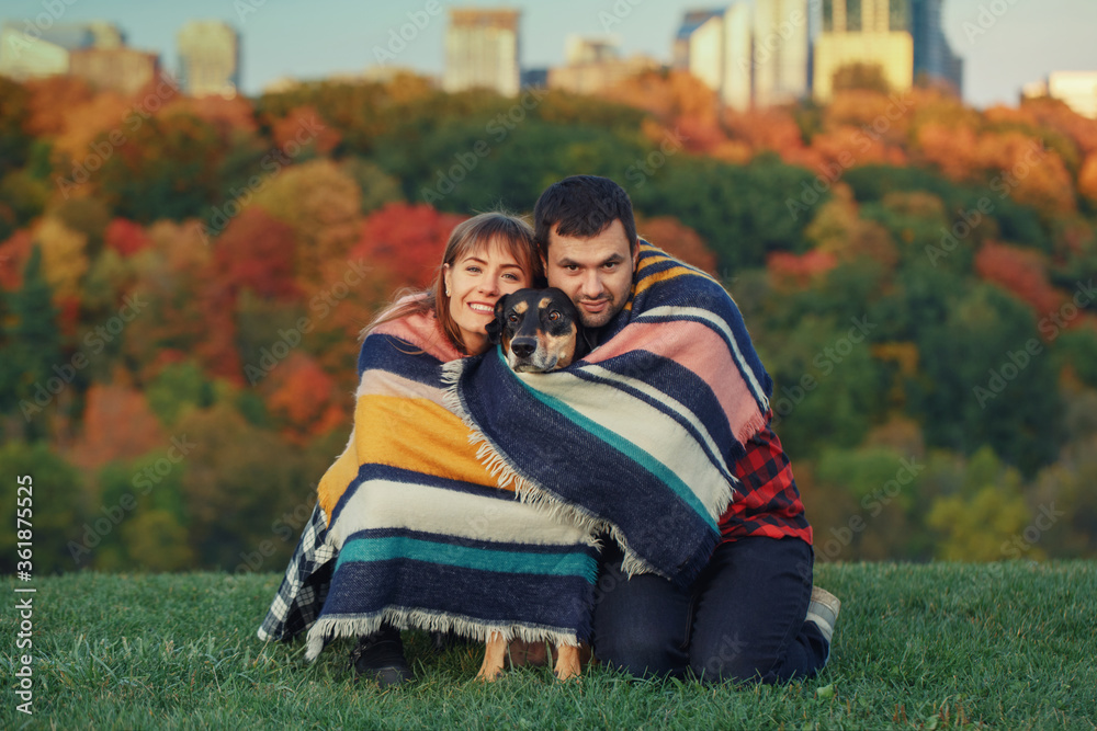 Beautiful young couple with dog in a park. Man and woman hugging playing with their domestic animal pet outdoor on autumn fall day. Family authentic lifestyle activity. Love and friendship. Beautiful young couple with dog in a park. Man and woman hugging playing with their domestic animal pet outdoor on autumn fall day. Family authentic lifestyle activity. Love and friendship.