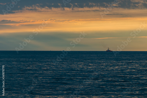 Sunset over sea water, after the thunderstorm. Full of clouds and vibrant colors over horizon.  And one thugboat waiting for oil tanker.  © Kevin