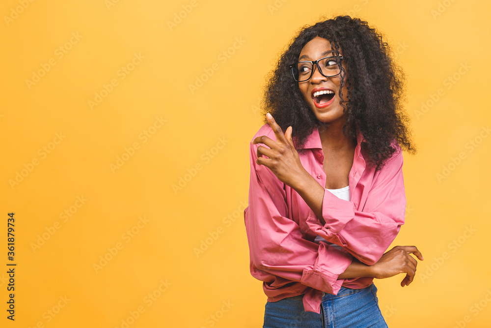 Portrait of cheerful young african american woman with curly hair posing in studio with happy smile. Dark-skinned woman smiling joyfully. Isolated over yellow background. Portrait of cheerful young african american woman with curly hair posing in studio with happy smile. Dark-skinned woman smiling joyfully. Isolated over yellow background.